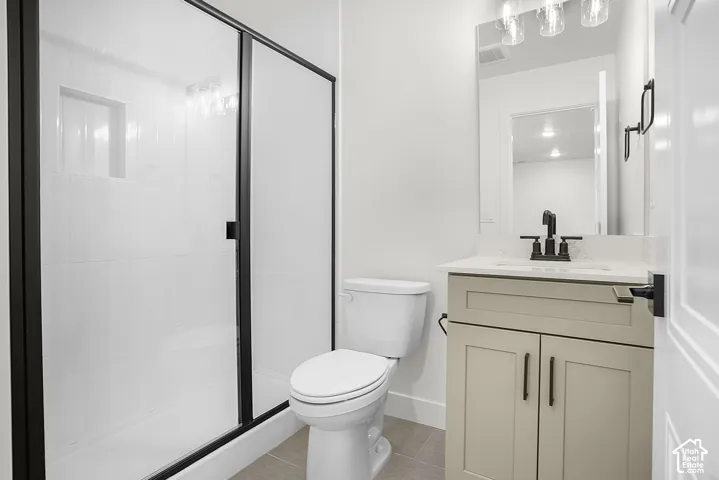 flex/bonus Modern bathroom featuring a glass-enclosed shower with matte black framing, a built-in shower niche, a single vanity with a light-colored cabinet, and a rectangular mirror with multi-bulb lighting
