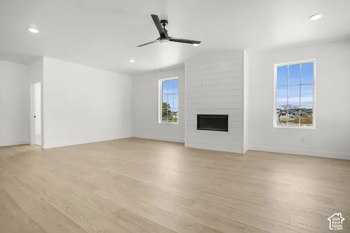 Spacious living area featuring wood-finish flooring, a contemporary fireplace with shiplap surround, and abundant natural light from large windows