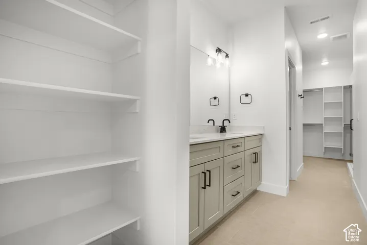 Primary Spa-inspired primary bathroom featuring a wood-finish dual-vanity with ample storage, quartz countertop, and chrome faucetry