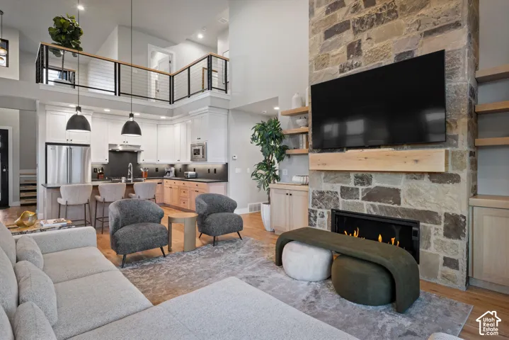 Open-concept living space with a stone-clad fireplace and wood mantel