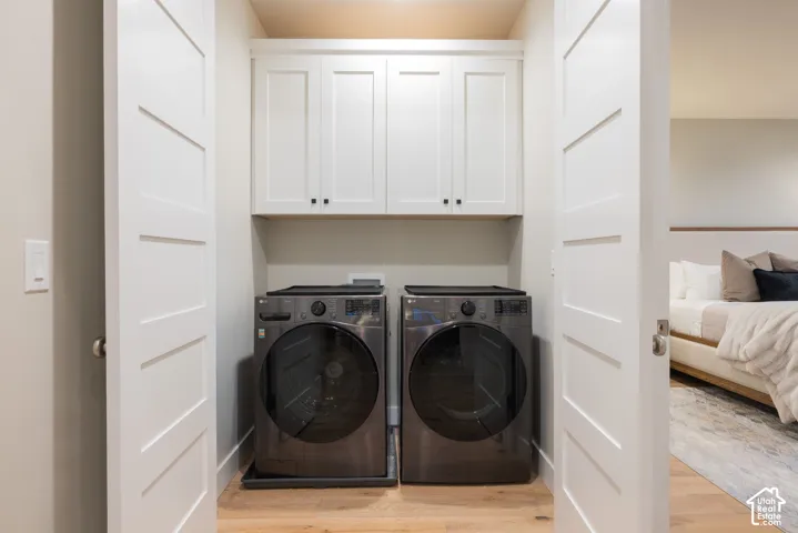Laundry closet featuring white shaker-style cabinetry, wood-finish flooring, and panel doors
