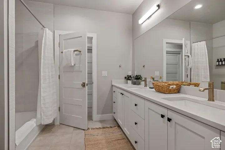 Dual vanity with integrated sinks, expansive counter space, wood-finish cabinetry, and brushed gold fixtures