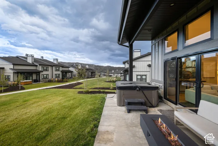 Covered patio with a built-in fire feature, a hot tub, and direct access to the interior through glass sliding doors