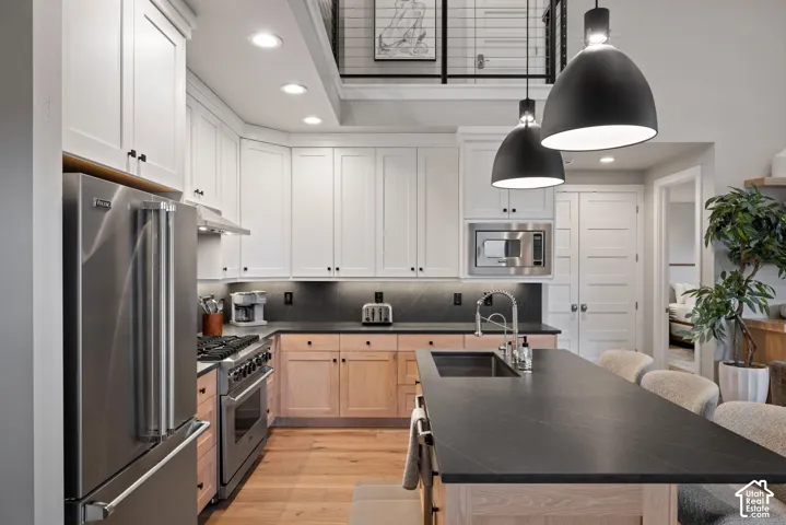 Modern kitchen featuring white upper cabinetry, wood-finish lower cabinetry, and stainless steel appliances