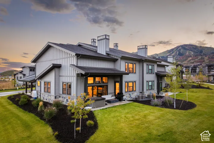Contemporary exterior with board and batten siding, stone accents, and multiple chimneys