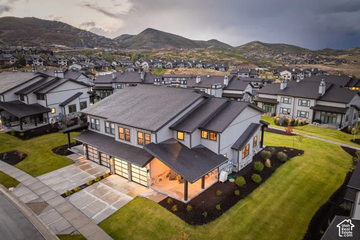 Modern exterior design with a dark metal roof, light-colored siding, and extensive landscaping