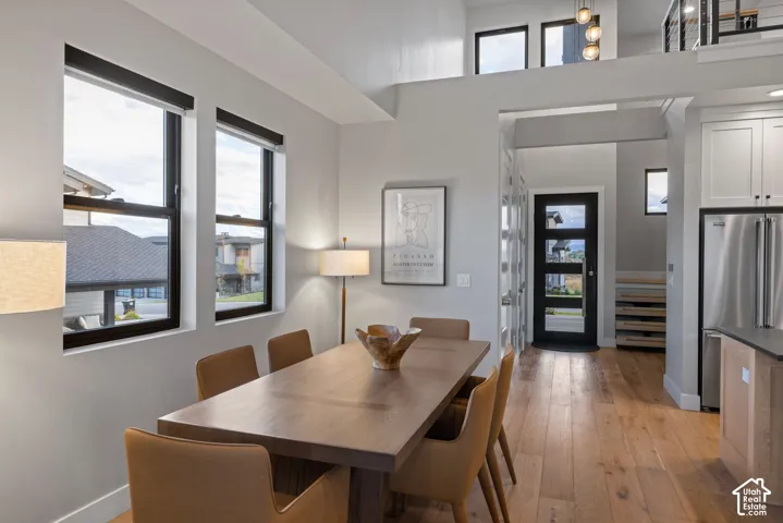 Open-concept interior featuring light wood-finish flooring, white walls, and black-framed windows