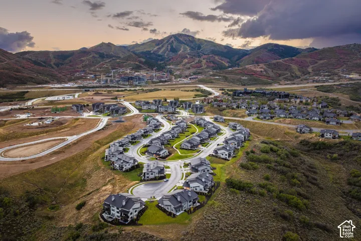 Spacious residential development featuring multiple modern homes with dark roofs, surrounded by undulating terrain and distant mountains