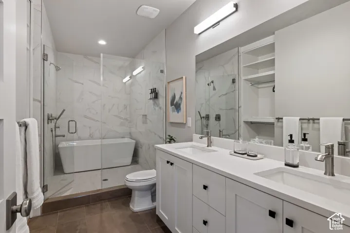 Dual vanity with white cabinetry and integrated sinks, a freestanding soaking tub, a glass-enclosed shower, large format wall tiling, and a built-in storage niche