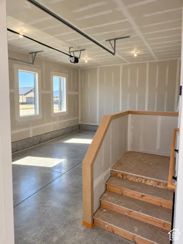 Concrete flooring, two windows, recessed lighting, raw wood staircase, wood railing