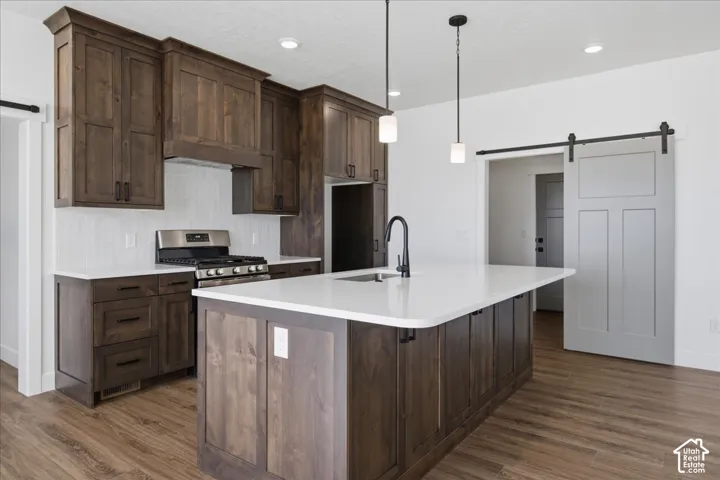 Kitchen featuring dark wood-finish cabinetry, a central island with white countertops, stainless steel appliances, and wood-finish flooring