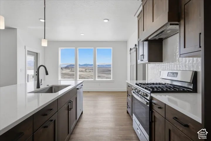 Chef's kitchen featuring dual gas ranges with stainless steel finishes, white quartz countertops, dark cabinetry with hardware accents, and a large triple-window opening framing panoramic landscape vistas