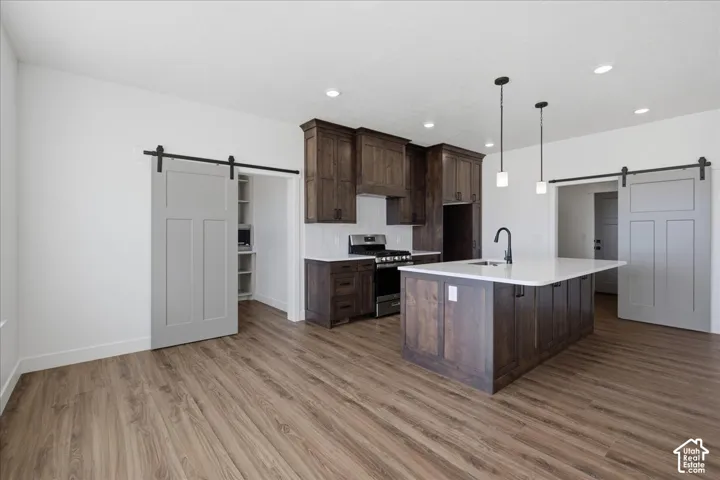 Modern kitchen featuring dark wood cabinetry, white quartz countertops, and a large island with waterfall edge