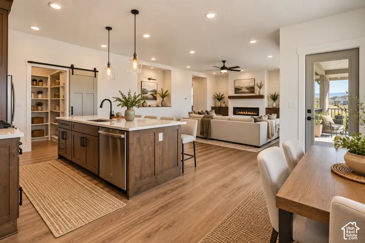 Spacious kitchen island with a built-in sink, wood-finish flooring, recessed lighting, and a barn door pantry