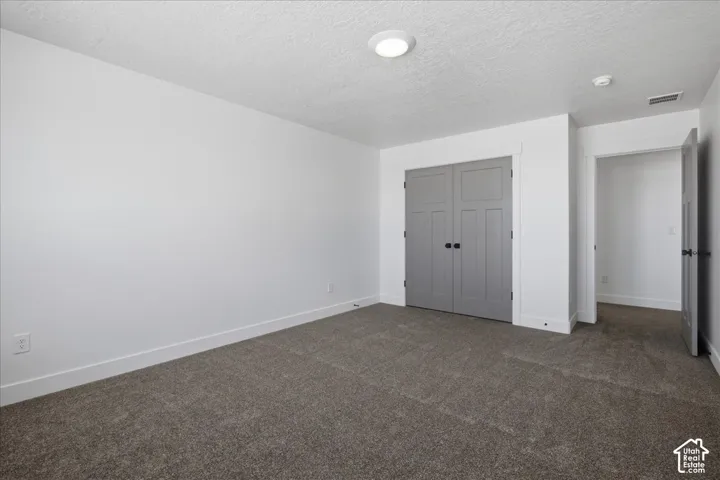 Spacious bedroom featuring neutral white walls, recessed ceiling lighting, and dual closets with six-panel doors