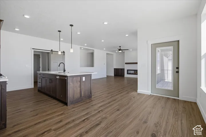 Kitchen island with white countertop, integrated sink, and dark wood-finish cabinetry