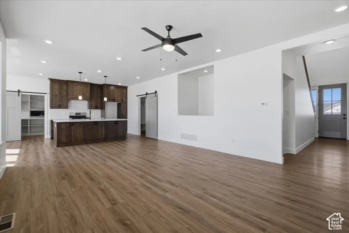 Open-concept living area featuring warm wood-finish flooring throughout, recessed ceiling lighting, and a modern ceiling fan