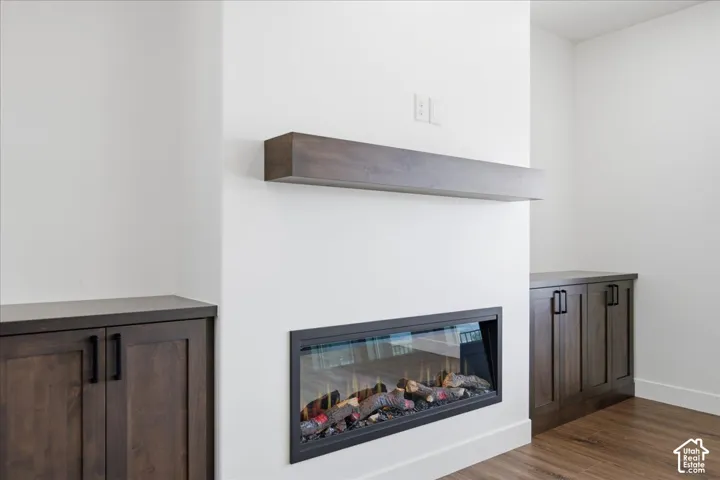 Modern fireplace focal point featuring a linear gas insert with realistic flame display, framed by clean white surround walls and a floating wood-finish mantel