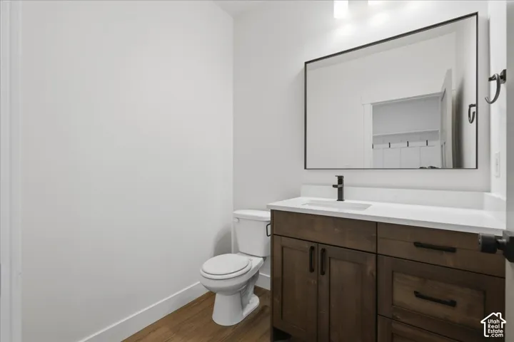 Wood-finish flooring, white walls, and a contemporary vanity with a white countertop