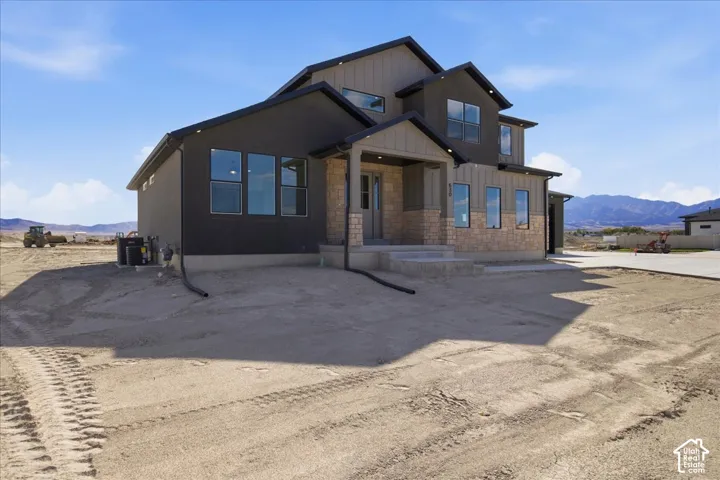 Contemporary architectural style with a multi-story design, stone and siding exterior, multiple window installations, and an integrated porch