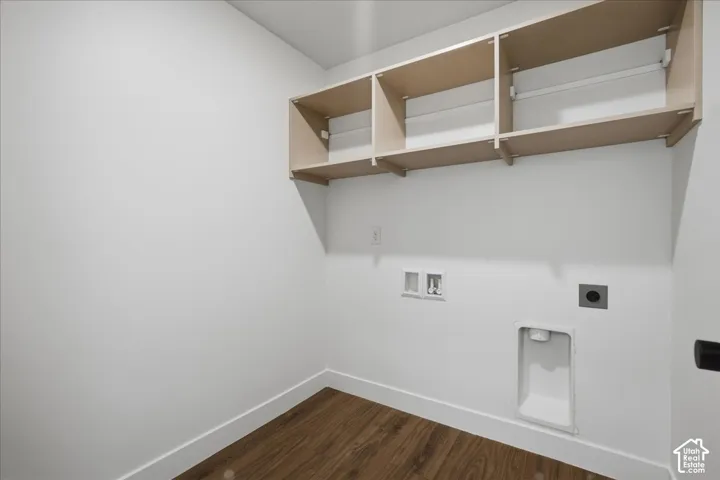 Laundry area featuring wood-finish flooring, white walls, built-in shelving, and utility hookups