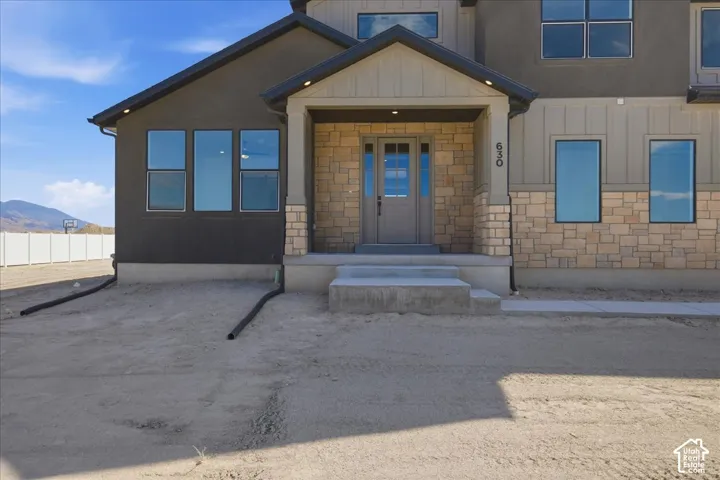 Modern exterior featuring stone and stucco finishes, a covered entry, and dark-framed windows