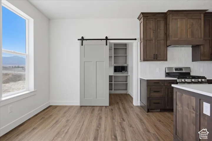 Modern kitchen featuring dark wood cabinetry, stainless steel appliances, and wood-finish flooring throughout
