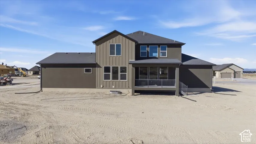 Contemporary exterior featuring a covered patio, multiple large windows, and a combination of vertical siding and stucco finishes