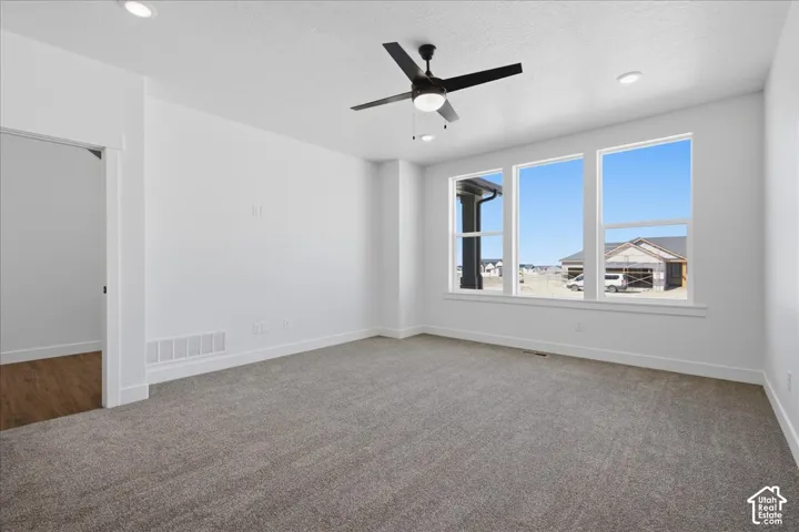 Expansive room featuring multiple windows, recessed ceiling lighting, a ceiling fan, and gray carpeting