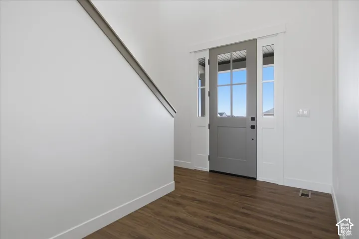 Entryway featuring a paneled door with glass inserts, two sidelights, and wood-finish flooring