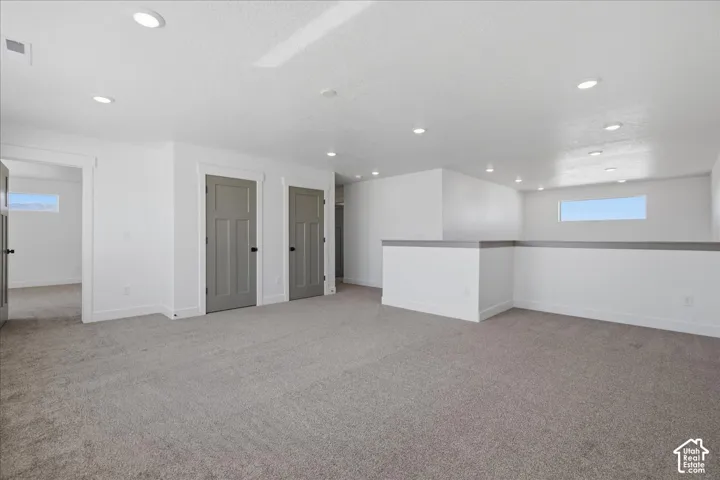 Recessed lighting, light gray carpet flooring, contemporary interior doors with dark hardware, white wall finishes, and a half-wall partition
