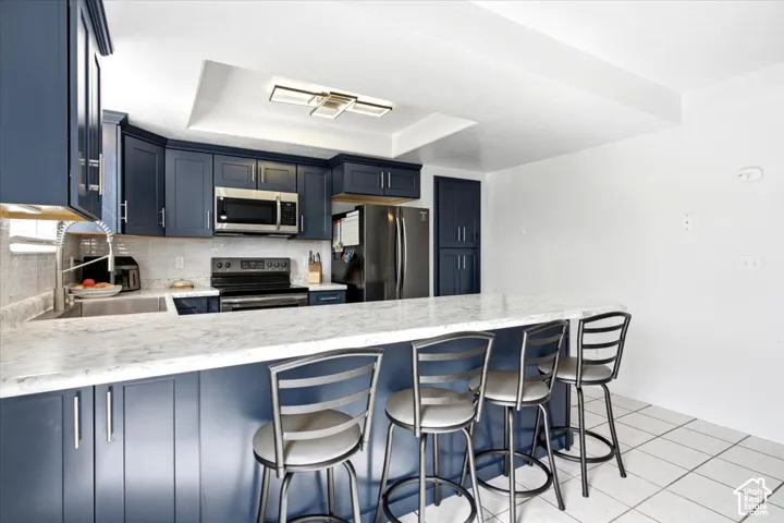 Kitchen featuring navy cabinetry, stone-finish countertops, stainless steel appliances, and a tile backsplash