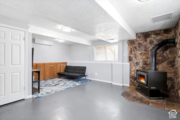 Stone accent wall with a wood-burning stove, built-in wooden cabinetry, and durable flooring