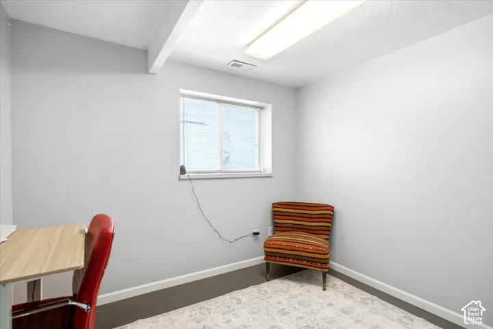 Window with horizontal blinds, light wood-finish flooring, white walls, and a fluorescent ceiling light