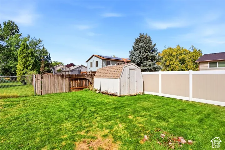 Expansive lawn with a storage shed, wood fence, and vinyl fence