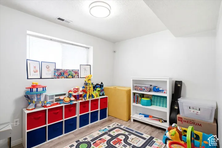 Recessed window with white blinds, wood-finish flooring, and a flush-mount ceiling light fixture