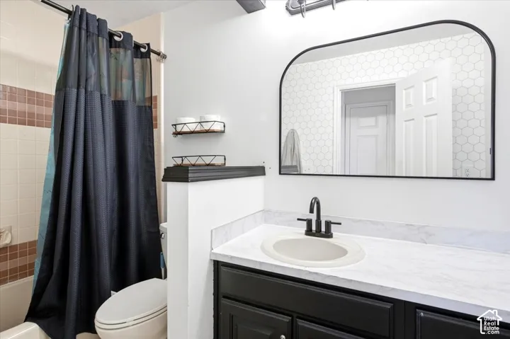 Bathroom featuring a black vanity with a white countertop, an oval undermount sink, a black faucet, and a black-framed arched mirror