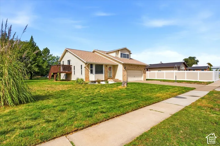 Single-family residence with an attached garage, featuring a raised wooden deck, a bay window, and a sidewalk