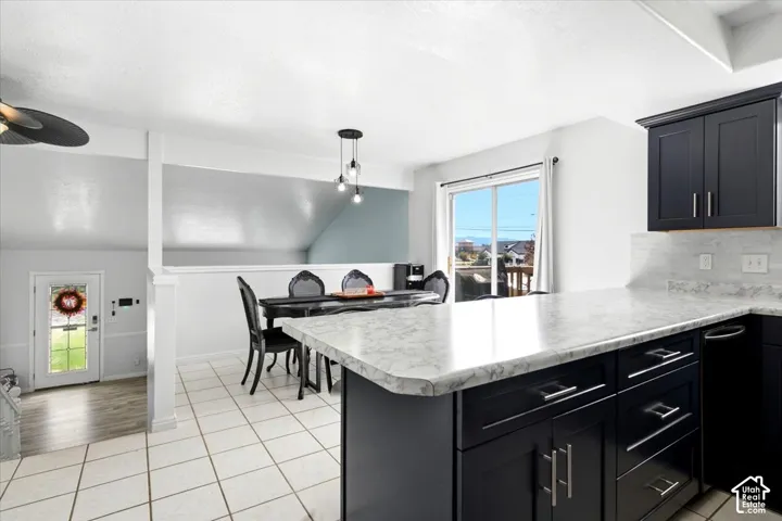 Kitchen featuring dark wood-finish cabinetry, light-toned countertops, and a white tiled backsplash