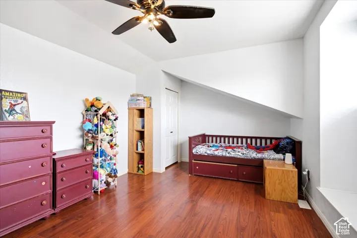 Wood-finish flooring with a ceiling fan light fixture, white walls, and a white paneled door