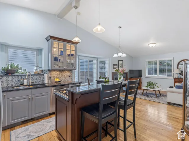 Kitchen featuring a mosaic tile backsplash, granite countertops, stainless steel appliances, and a central island with bar seating