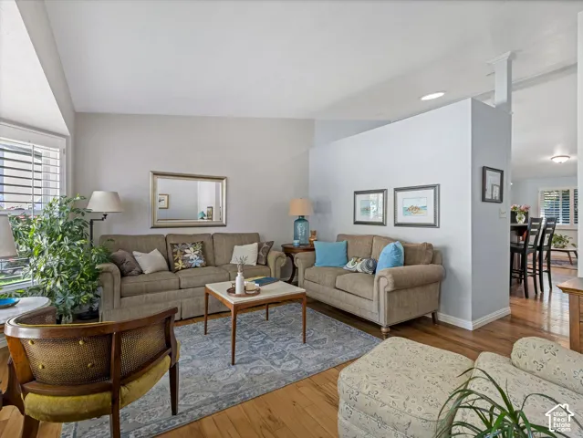 Living area featuring wood-finish flooring, a partial wall, and recessed lighting