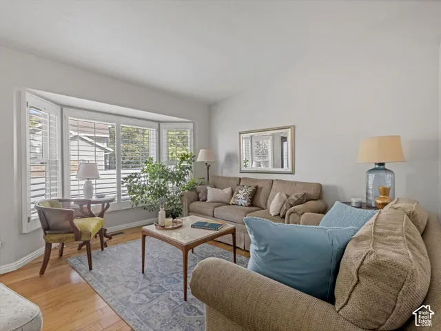 Bay window with plantation shutters, light wood-finish flooring, and neutral wall tones