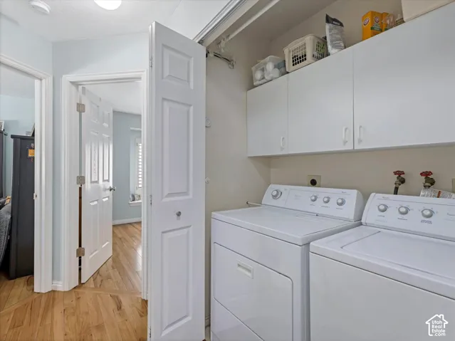 Laundry area featuring upper cabinetry, a mounted clothes hanging rod, and wood-finish flooring