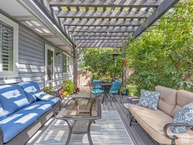 Covered pergola with slatted overhead structure provides dappled natural light over a composite deck