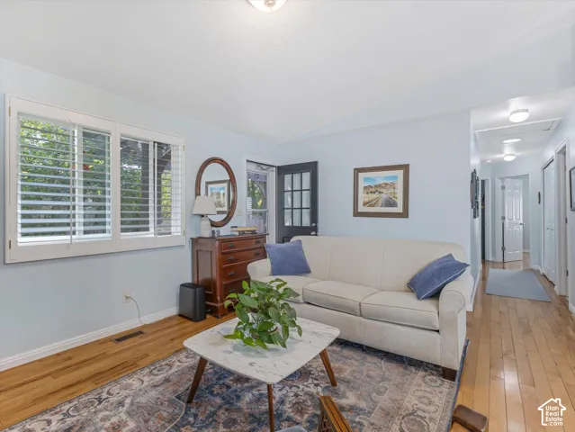 Wood-finish flooring throughout, white plantation shutters, and a dark-paneled exterior door