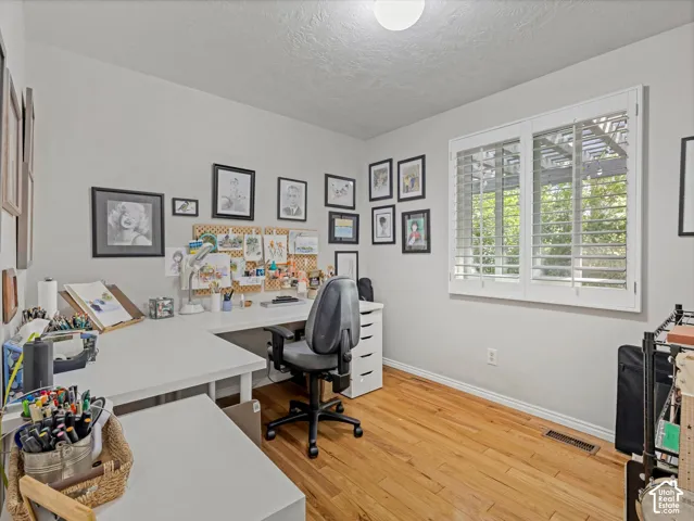 Hardwood flooring, neutral wall tones, window with white plantation shutters, and a flush mount ceiling light
