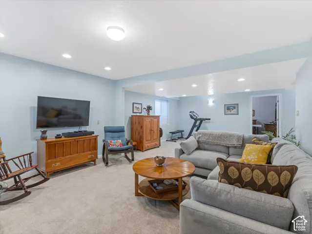 Recessed ceiling lighting, light blue wall paint, light-toned carpet flooring, built-in shelving, and a wall-mounted television