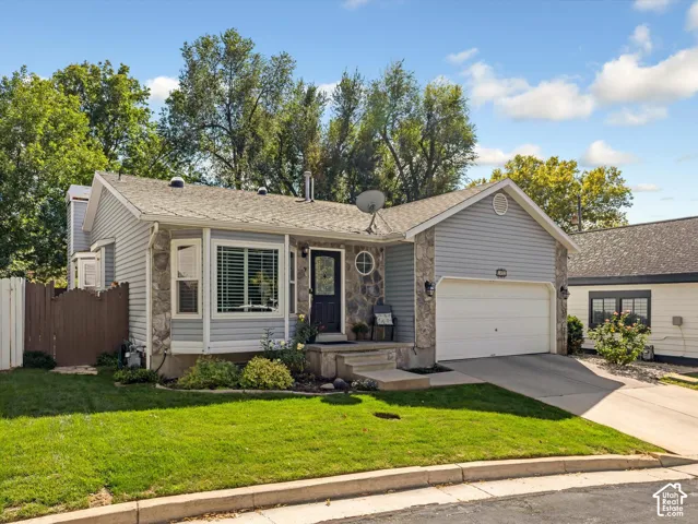 Stone facade with light gray siding, attached garage, and bay window