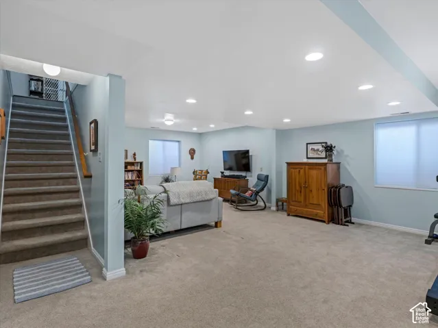 Carpeted flooring throughout, recessed lighting, and a window with privacy covering
